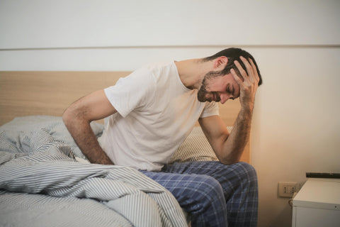 Man sitting on bed suffering from fatigue caused by low potassium levels