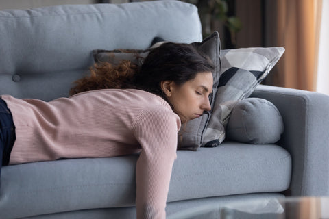 Exhausted young Caucasian woman lying on comfortable sofa in living room sleeping after hard-working day, tired female falls asleep on couch at home, due to low potassium