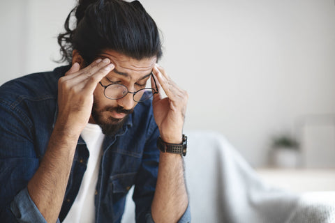 Young guy suffering from headache after hard working day Needing caffeinated drinks