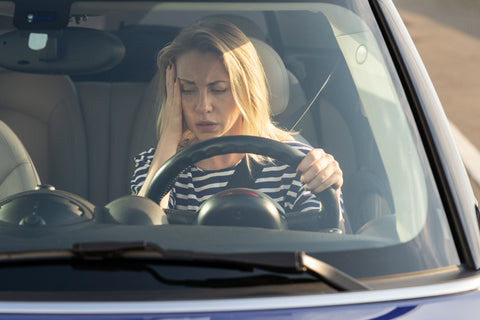 Woman with a headache on a long drive from being too tired to drive