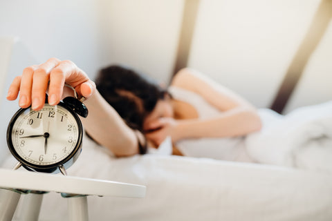 Woman in bed hits the snooze button instead of drinking a sugar free energy drink