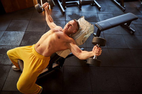 Man in yellow sweatpants lifting heavy weights 