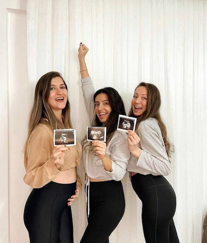 ic:Pregnant best friends in their 1st trimester holding ultrasounds in leggings