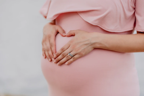 ic:Pregnant woman making a heart with her hands over her belly