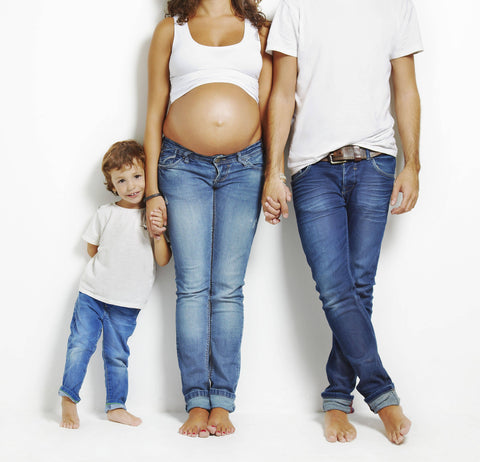 ic:pregnant mom in jeans taking family photos on a white background