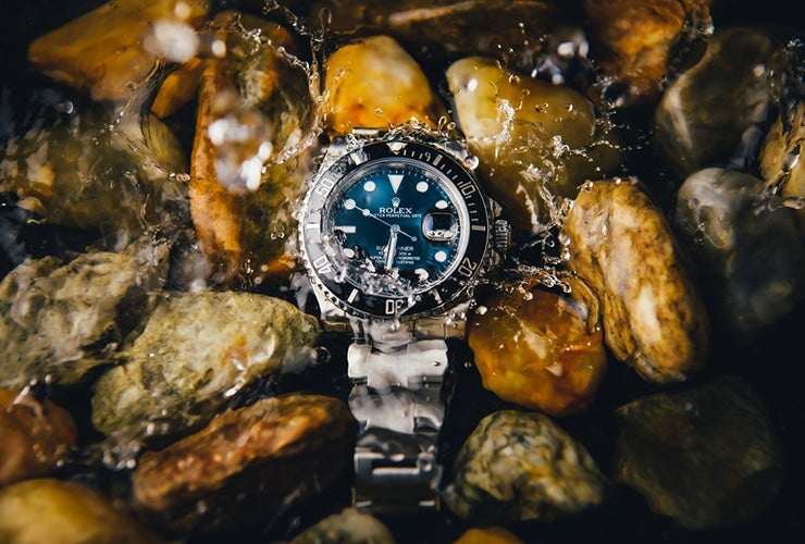 a rolex dropping into a shallow creek with rocks