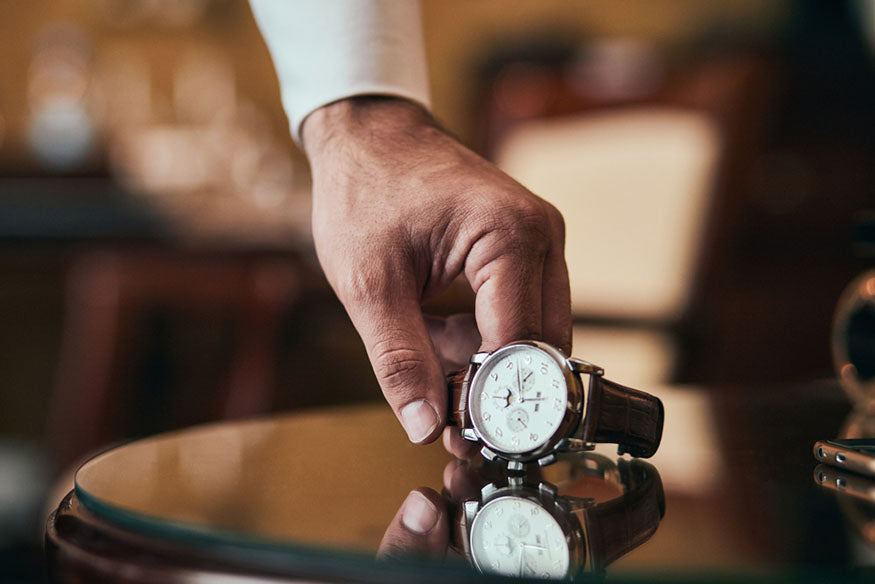 hand setting luxury watch on table