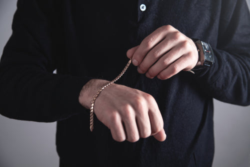 homme mettant un bracelet en or