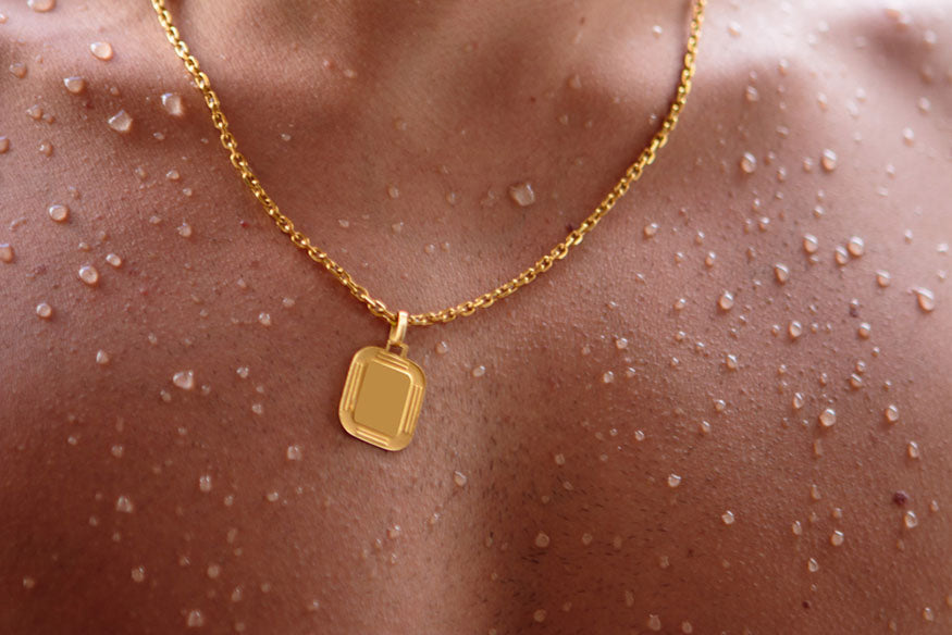 a man wearing a gold chain with a pendant shirtless