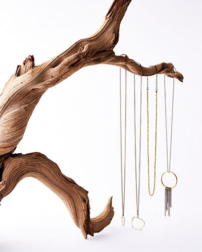 necklaces hanging from twisted driftwood branch