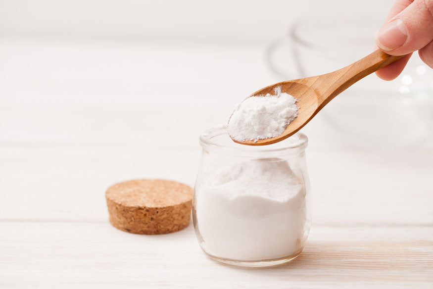 spooning baking soda into jar