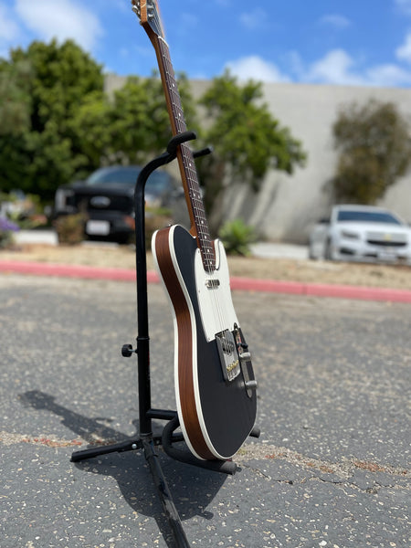 Photograph of a Jennings Guitars 'Navigator' model, telecaster style handbuild guitar. Black body with parchment binding, parchment pickguard, rosewood fingerboard. 