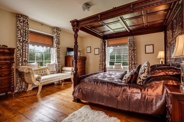 Ancient civilizations influence on innerspring mattresses and memory foam illustrated by a furnished Victorian era bedroom with a carved four poster bed and ornate decor