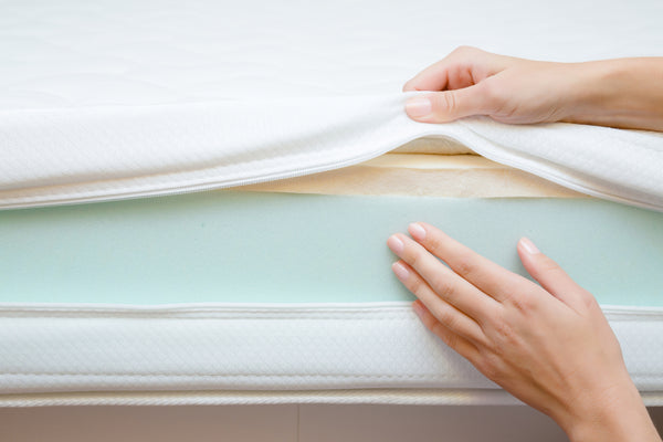 Exploring memory foam origins and development in material science for pressure relief demonstrated through womans hands touching mattress layers