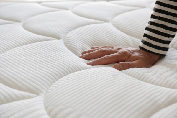 Man testing mattress firmness for comfort and support on a white orthopedic mattress