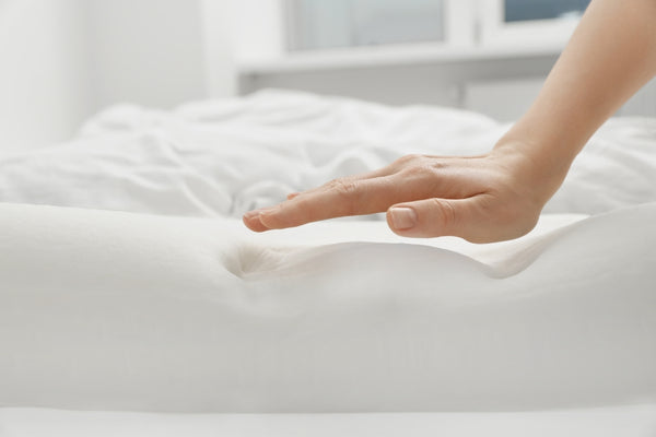 Pressure relief and body support with material science in memory foam mattresses demonstrated by a woman with an orthopedic pillow