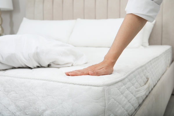 Woman assessing mattress firmness as a sleep solution for back pain relief