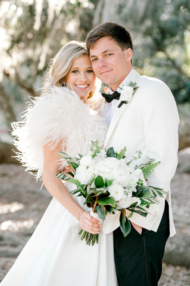 Bride and groom portrait wearing white and black. Bride holding a white bouquet.