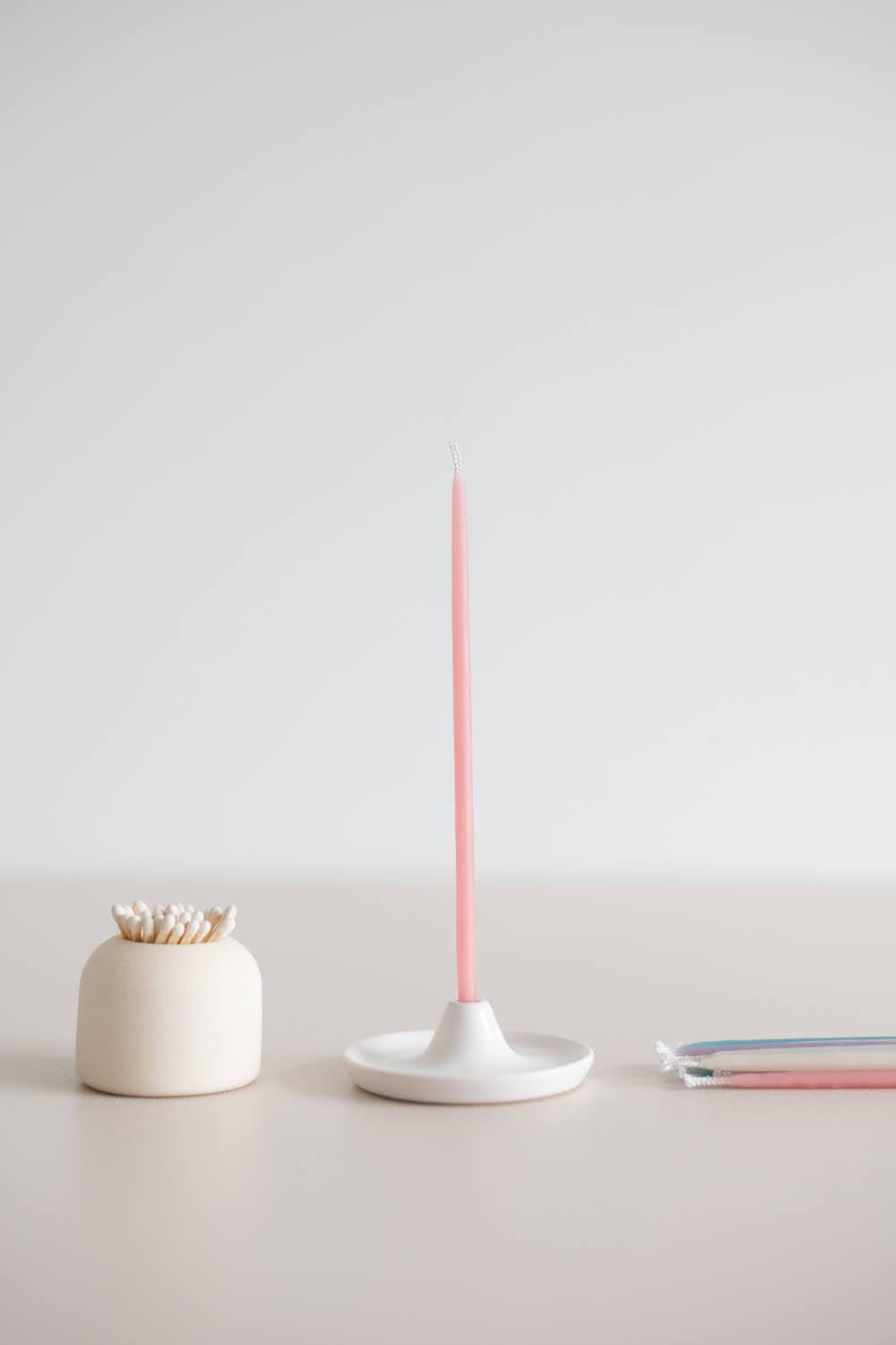 Giving Set in pastel with pink beeswax candle in ceramic candle holder beside a ceramic match striker.