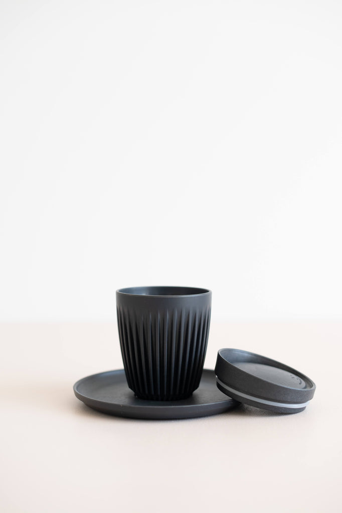 8 oz coffee cup in charcoal colour on top of a saucer with the lid beside it.