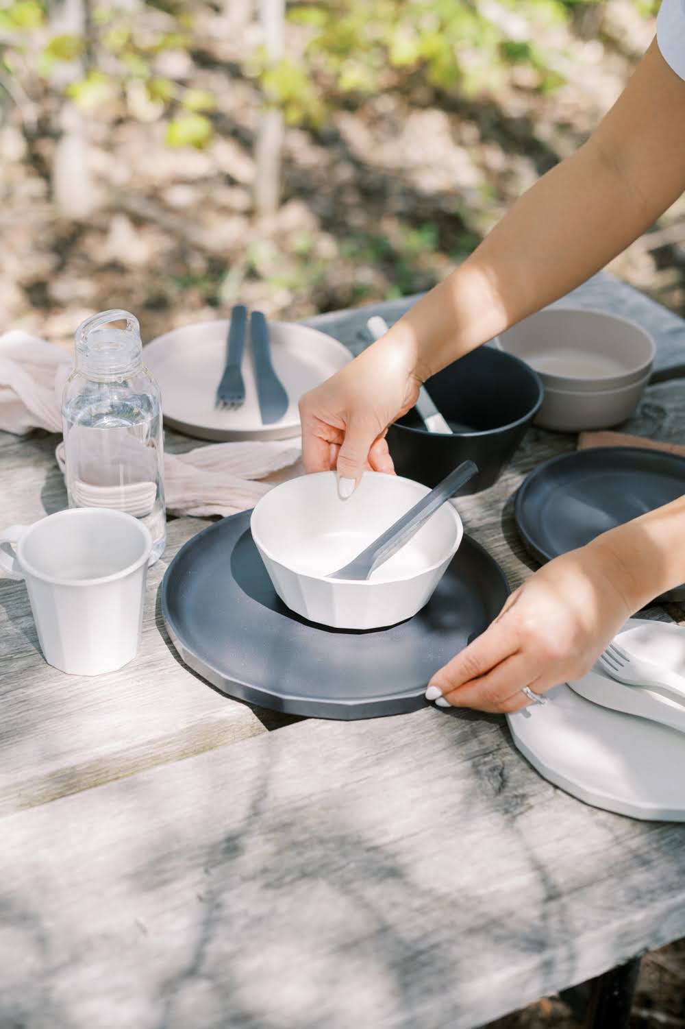 Alfresco dining, bamboo bowls, spoons, utensils and water bottle on picnic table in the woods