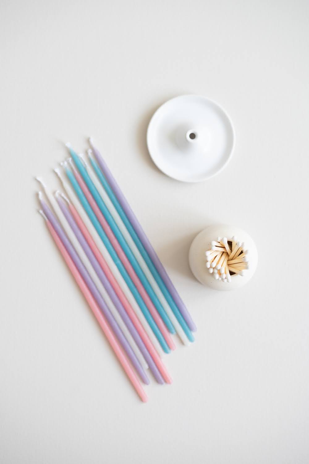 Flat lay of the pastel Giving Set that includes beeswax gala candles, ceramic candle holder and a ceramic match striker.