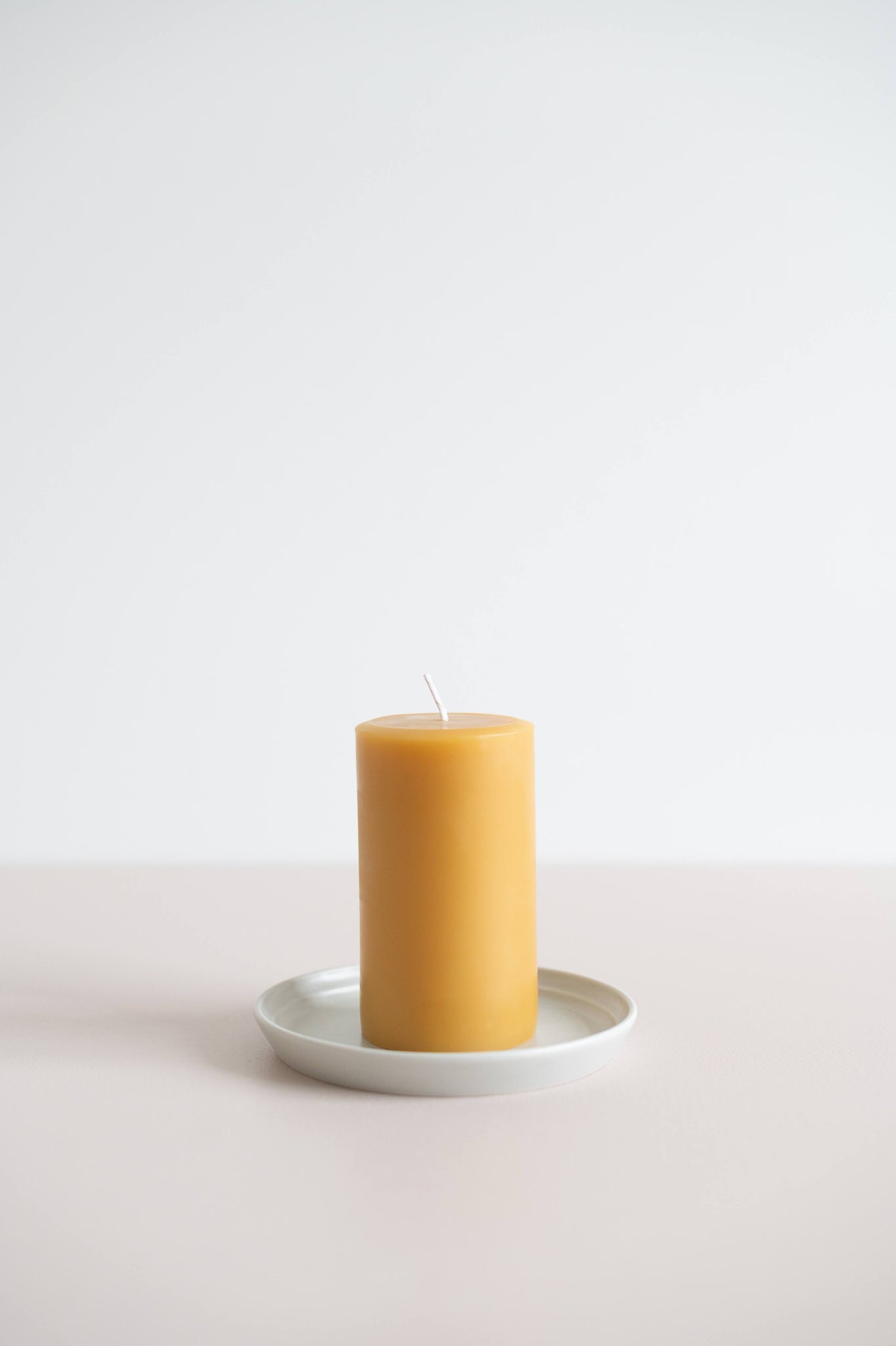 Natural round beeswax pillar candles on a Fog Appetizer Plate