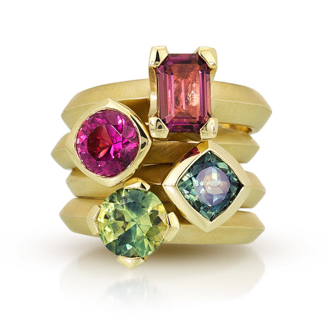 photo of four colored gemstone solitaires in fairmined 18k yellow gold - the top two are pink tourmaline, the bottom two are blue and green sapphire