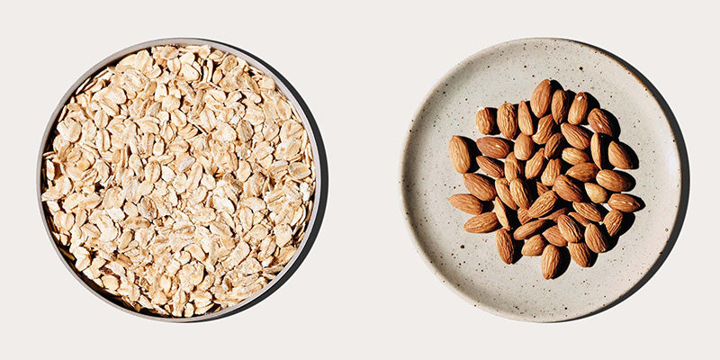 a bowl of oats next to a plate full of almonds