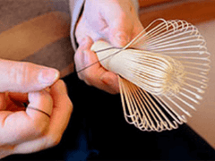 Hand weaving thread around tines of a bamboo whisk