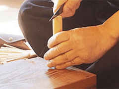 Hand slicing into piece of bamboo with a knife