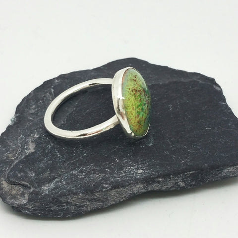 Ring made with a green copper enamel cabochon set in a sterling silver bezel.