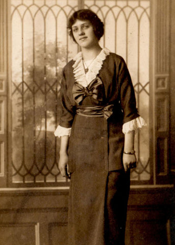 Busia in her 20's dressed in formal wear with leaded glass window behind her.