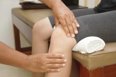 A physical therapist examines a patient's knee