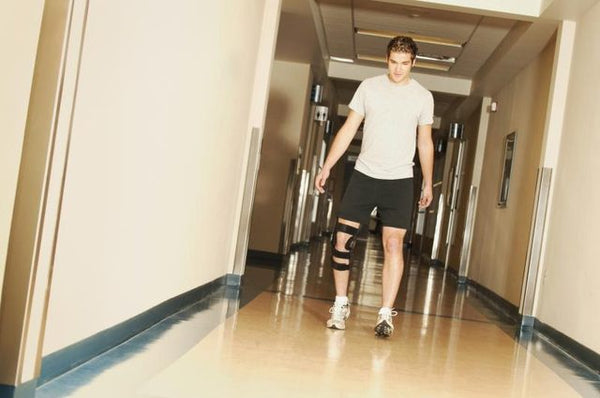A man wearing a knee brace walks down an hospital corridor