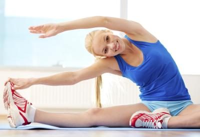 A young woman is doing stretches in the gym.