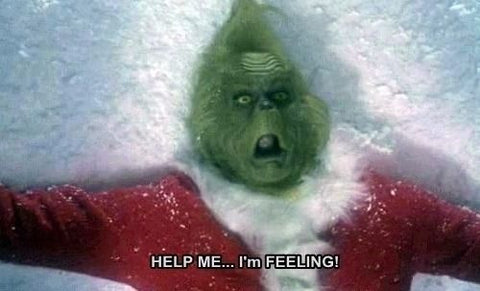 grinch lying in the snow, looking shocked with text that says "Help me.. I'm feeling!"