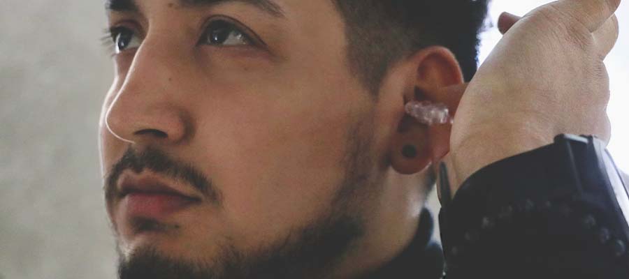 Man is inserting transparent earplug into his left ear