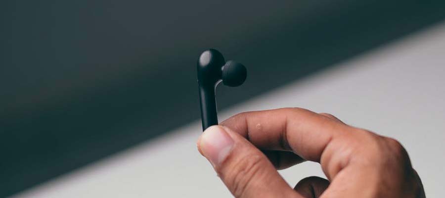 Fingers holding the black earbud