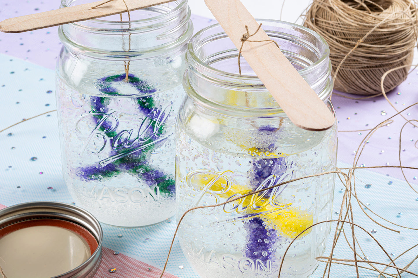 Closeup image of borax pipe cleaner crystals being made in jars with string and sparkles in background