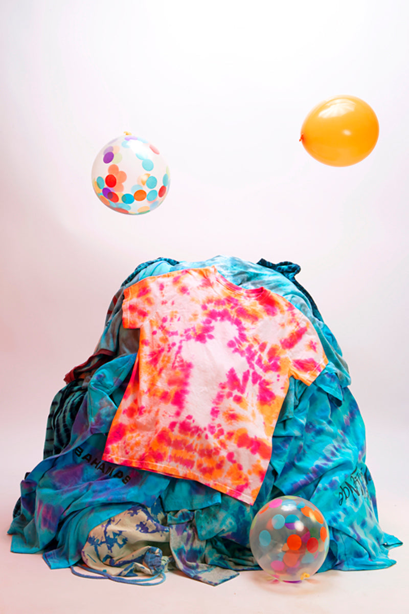Orange and pink tie dye cross t-shirt on top of blue tie dye shirts with balloons