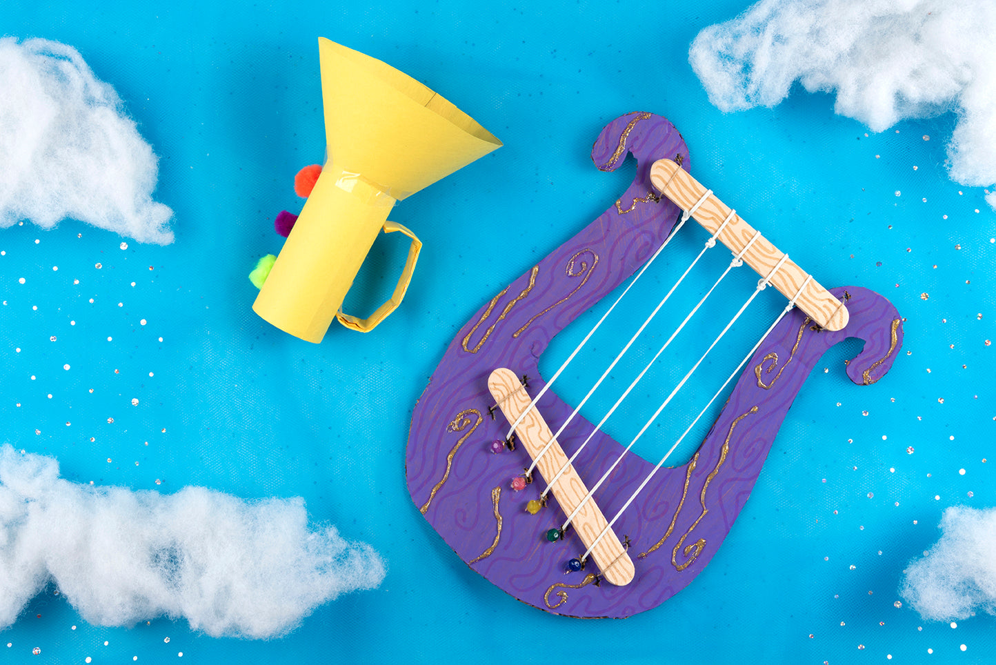 Kid's Bible craft praise instruments against a blue sky background with clouds and glitter rain