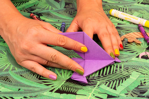 Noah's Arc Origami closeup of folding purple origami bird with colorful nails on foliage background