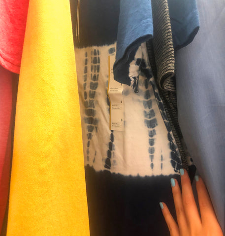 Closeup of Shibori tie dye style top on a garment rack between red, yellow, and grey shirts at Target