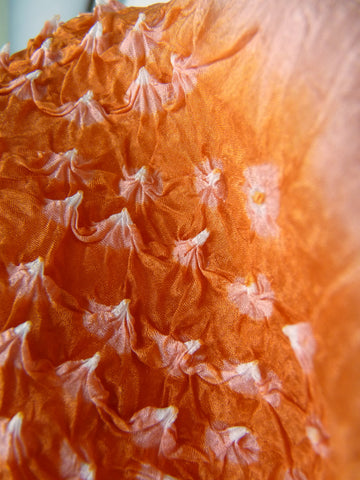 closeup of orange scarf tie dyed in bandhani technique