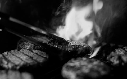 Person Grilling Hamburgers on Open Flame Black and White Monochrome Image