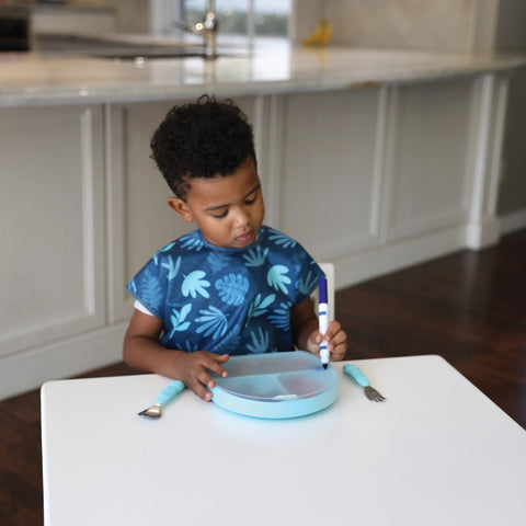 child writing on a divided plate lid