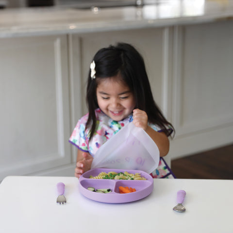 child opening divided dish with lid