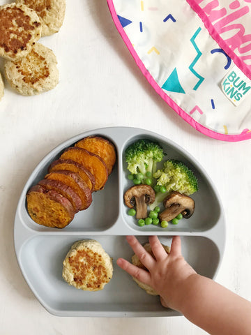 baby reaching for food in a toddler plate