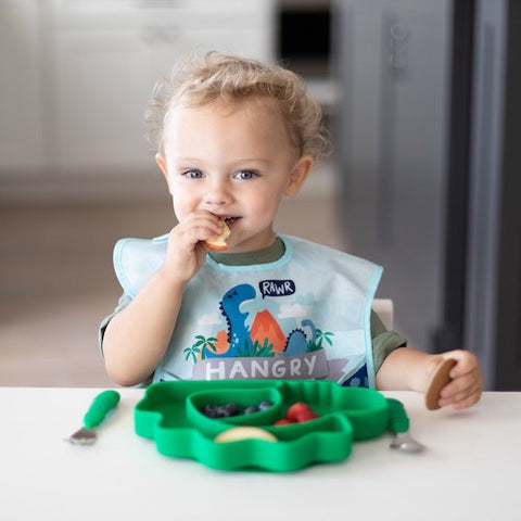 toddler eating out of dinosaur plate in hangry bib